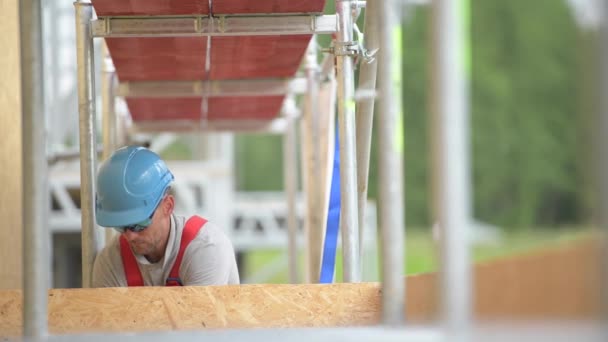 Kaukasiska entreprenör arbetare i sin 30s på en byggnadsställningar. Arbete på hög höjd. — Stockvideo