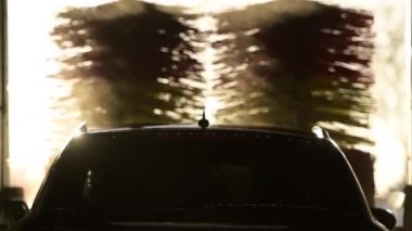 Car in the Automatic Car Wash. Spinning Brushes in Slow Motion During Sunset.