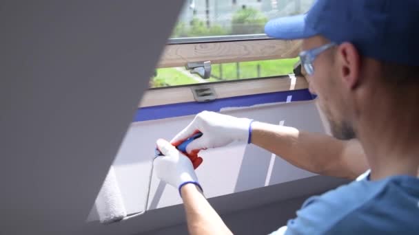 Kavkazské muži Malování jeho pokoj. Konečná úprava hran střešní okno. Místnost téma malíř. — Stock video
