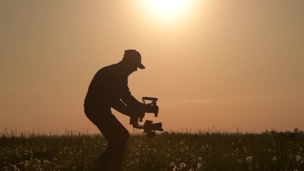 Opérateur de stabilisateur vidéo. Prendre des photos vidéo à l'aide de l'équipement de cardan DSLR. Sunset Silhouette Concept . — Video