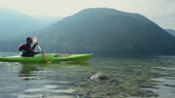 Kajaktour auf dem malerischen See. Kaukasischer Kajakfahrer paddelt in seinem Kajak. — Stockvideo