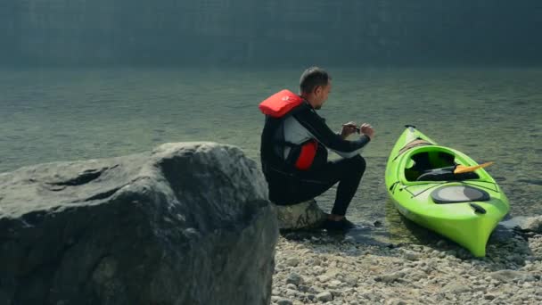 Kayaker i jego kajak na brzegu jeziora przygotowanie do innego kajak wycieczka — Wideo stockowe