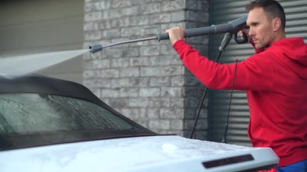 Kaukasische Männer benutzen Hochdruckreiniger, um sein Auto zu waschen. — Stockvideo