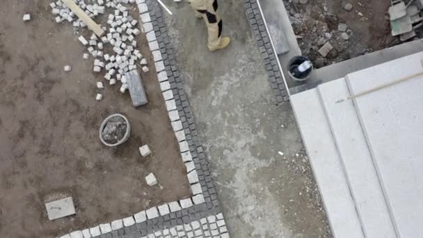 Tegelstenar uppfart byggnad. Kaukasiska byggnadsarbetare efter behandling granit tegel väg. — Stockvideo