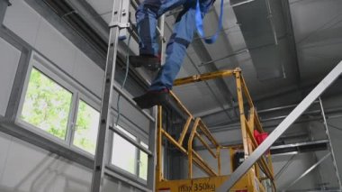 Hava Kanalı Yükleyicisi İskeleden aşağı iniyor. Emniyet kemeri takılı.. 