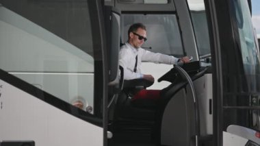 Toplu Taşımacılık Erkek Otobüs Şoförü Kabininde oturuyor ve açık kapıdan bakıyor. 