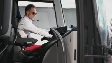 Beyaz erkek otobüs şöförü Araç Kabinindeki kapı ve kapakları kontrol ediyor ve ayarlıyor. 