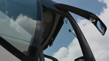 Büyük dış aynaları ve şoför kabinine ve yolcuların oturduğu açık kapısı olan büyük bir toplu taşıma otobüsü manzarası. 
