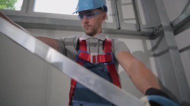 Erkek İnşaat İşçisi Metal İnşaat Yapısını Ticari Binanın içine Kuruyor ve Ayarlıyor 