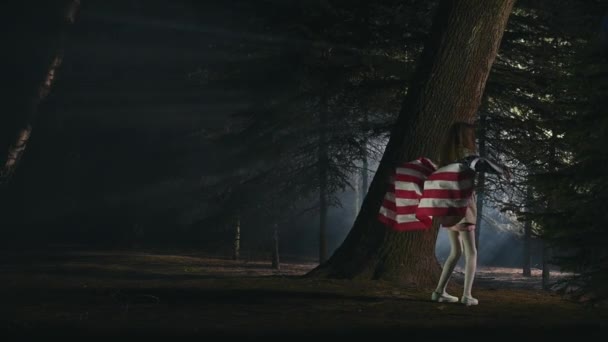 若い女の子の夜のシーン大きなアメリカ国旗を振って森の中で踊る — ストック動画