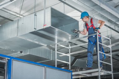 40 'lı yaşlarındaki beyaz tenli teknisyen yeni yeni kurulmuş depo havalandırma sistemini test ediyor. Ticari Isıtma, Soğutma ve Havalandırma Sistemleri.