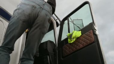 Kafkasyalı adam büyük teslimat kamyonunun yolcu koltuğuna tırmanıyor ve koltukta rahatça oturuyor.. 