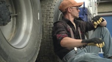 Çok çalışan ticari sürücünün kapanışı. Yere oturmuş, dinleniyor ve nöbet tutuyor.. 