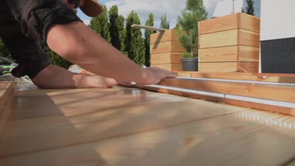 新しく改造された木製パティオで狭いストリップライトを組み立てる造園請負業者 — ストック動画