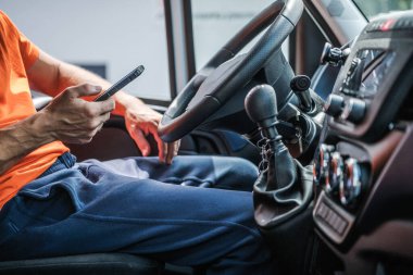Kafkas Teslimat Aracı Sürücüsü akıllı telefonunu kullanarak interneti tarıyor. Araç İçi.