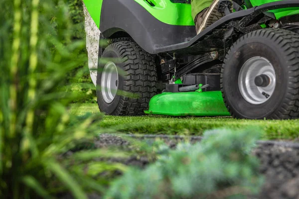 造園と園芸のテーマ プロの乗馬ガーデントラクター機器を使用して裏庭の草の刈り — ストック写真