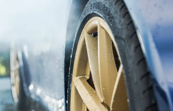 車の中のエキゾチックな車の洗浄水で覆われた黄金の合金ホイールが閉じます 自動車と交通のテーマ — ストック写真