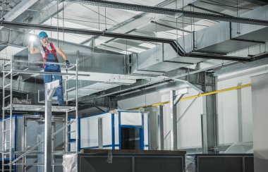 Ticari Bina 'da, Flashlight Nezaret Bakışlı Profesyonel Havalandırma Teknisyeni. Kırklı yaşlarda beyaz bir işçi. Endüstriyel Tema.