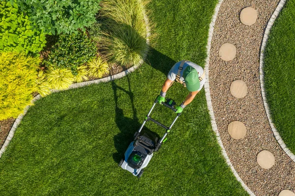 コードレス電動芝刈り機を使用して裏庭の芝生を刈る白人庭師 空中展望 造園業 — ストック写真