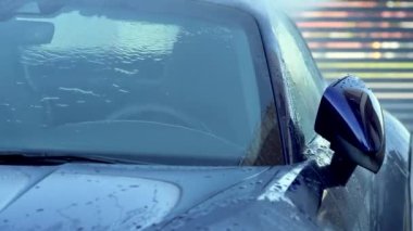 Biri yüksek basınçlı su püskürtüsüyle araçtaki kiri temizlerken yakın çekim. Manuel Yaz Araba Yıkama Evi. 