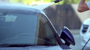 Yetişkinlerin çatısı ve modern arabanın ön camına yüksek su basınçlı hortum ve değnekle yakın çekim yapın.. 