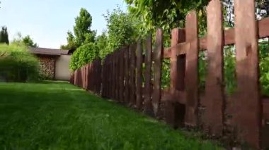 Kahverengi Lekeli Ahşap Çit Yeşil Çim Bölümü Konut Bölümü. Arka bahçesinde ağaçlar ve çalılar olan doğal manzara.. 