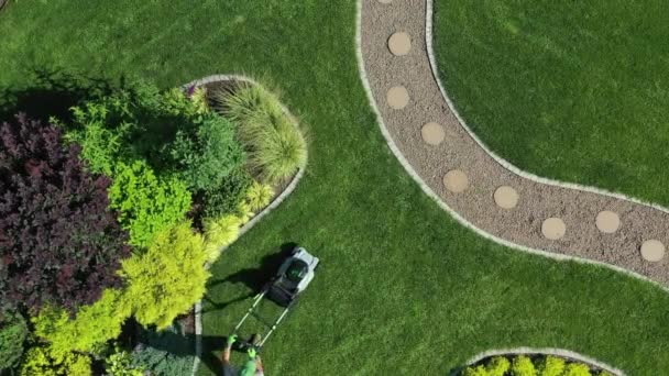 专业的男性园艺师在妥善保管的土地上开辟大面积的绿色草坪 设计精美 植物种类繁多的园林的空中景观 — 图库视频影像