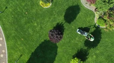 Orta Çağ bahçıvanı, çim biçme makinesiyle yeşil çimenlikte fazla büyümüş çimleri biçiyor. Bahçe 'de Yaz Çalışmaları ve Havadan Bakış Alanında Taze Çimen. 