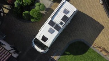 Özel garaj yolunda park edilmiş orta büyüklükteki araçların hava görüntüsü. Çatı üzerine kurulu güneş panelleri olan kamp minibüsü geziye hazırlanıyor..