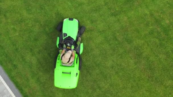芝生のケアに白人男性庭師の空中ビュー乗馬芝刈りプライベートプロパティ上の新鮮な草 — ストック動画