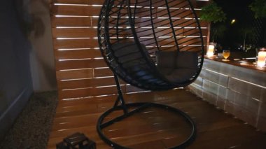 Geceleri tahta güvertede boş Oval Sandalye. Huzurlu Arka Bahçe Işıklar ve Mumlardan Parlak.