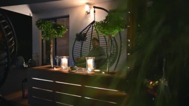 Geceleri Asılı Yumurta Sandalyesi Tahta Masa Dekorasyonu ve Aksan Işığı ile Modern Veranda Dekorasyonu. 