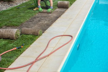 Bahçe düzenleme işçisi Doğa Çimenliği Turları 'nı Yuvarlamaktan Açık Hava Yüzme Havuzu' na Kuruyor. Bahçe ve Peyzaj Endüstrisi TemasıName.