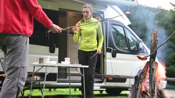 年轻的白种人朋友在篝火和户外食物的露营地一起消磨时间 — 图库视频影像