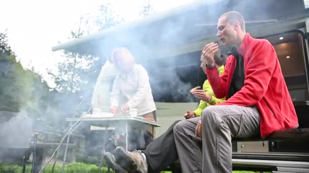 キャンプファイヤーとキャンパー ヴァンの前のキャンプで一緒にぶらついている白人の友人 — ストック動画