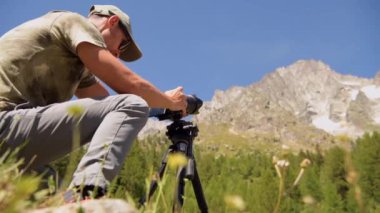 40 'lı yaşlarındaki beyaz fotoğrafçı yaz gezisi sırasında fotoğrafçılık öğreniyor. Fotoğraf Çekme Tripod Kullanıyor.