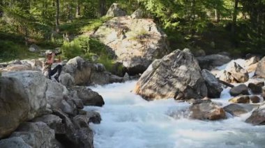 40 'lı yaşlarda, Alp Nehri kıyısında modern kamera ve tripodu kullanarak doğanın fotoğraflarını çeken beyaz adamlar.
