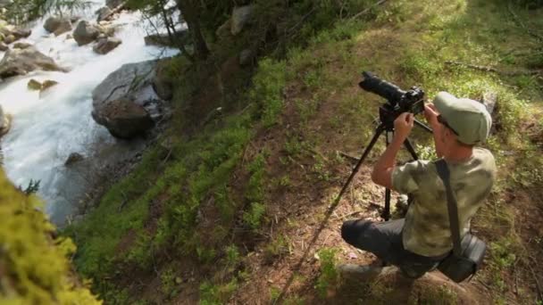 Фотограф Фотоаппаратурой Берегу Горной Реки Живописном Альпийском Регионе — стоковое видео