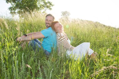 iki yaz çimen sonra günbatımı üzerinde gülümseyen. mutlu bir adam ve alan arkaya oturan kadın