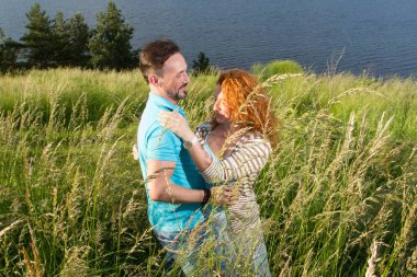 Genç bir çift daha önce yağmur dansı. iki kişi ve aşık mutlu çift. Casual adam ve yeşil çim boyunca denizin karanlık suya karşı doğada yürüyüş ile kadın.