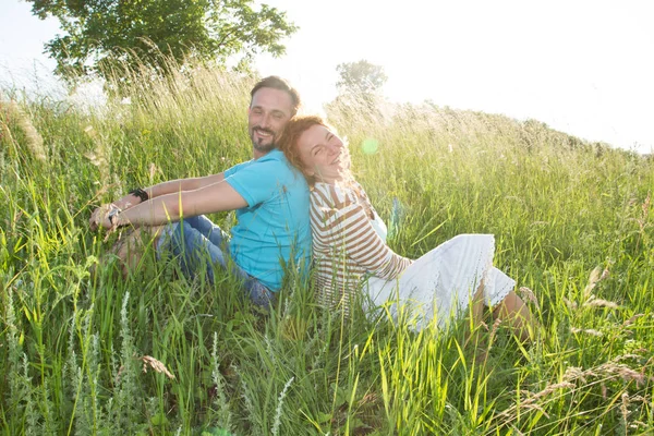 iki yaz çimen sonra günbatımı üzerinde gülümseyen. mutlu bir adam ve alan arkaya oturan kadın