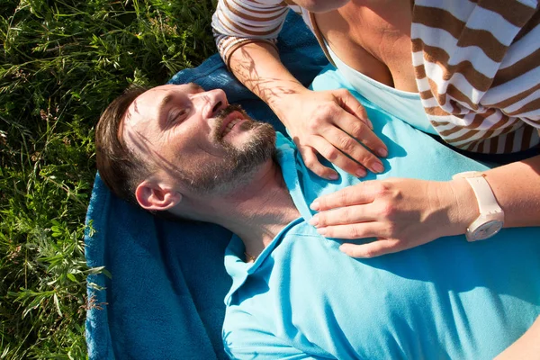 Kadınla adam portresi göğsünde eller. Gülümseyen adam mavi battaniye ve kız arkadaşı elleriyle yeşil çim döşeme