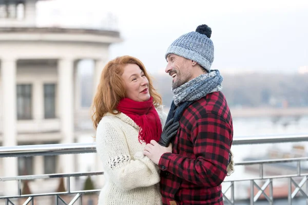 Happy guy looks to woman. Urban couple date on bridge. Red hair woman meet smiling guy. Surprised woman and laughing men