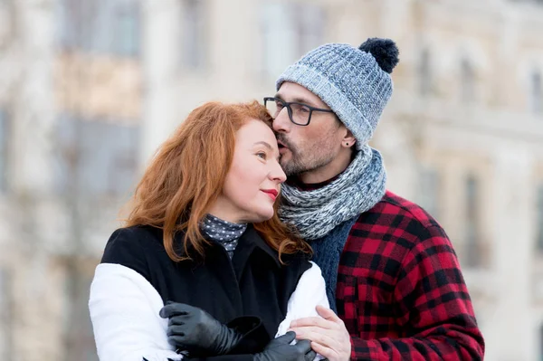 Man kissing woman in forehead. Man in glasses kissing woman. Guy embracing girl and kiss. Urban people love outside dates. Family loves outside traveling