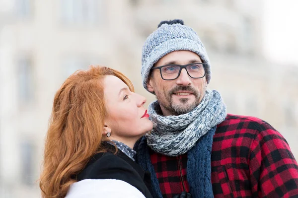 Brunette woman going kissing man. Red hair woman looking to guys face. Portrait of happy couple. Bearded guy in glasses and loving woman with red lips.