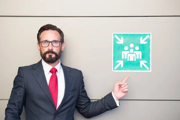 Handsome professional leader pointing to meeting point sign. Man in suit and red tie warning about place for meeting. Meeting point for young businessmen and entrepreneurs. You can meet here!