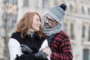 Güzel kadın şapkalı adamı tarafından kucakladı. Adam gözlüklü esmer saçlı kadın tutar. Kentsel kişi sokakta Toplantı.