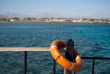 Lifebuoy bariyer üzerinde. Turuncu Lifebuoy ve masmavi bir deniz. iskelede ekipman kurtarmak. Lifebuoy sütun yakın çekim.