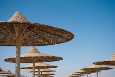 Şemsiye kubbe mavi gökyüzü arka plan satırlarda. Plaj şemsiyeleri kubbeleri örgülü. Arka plan mavi gökyüzü ve rattan kubbeler