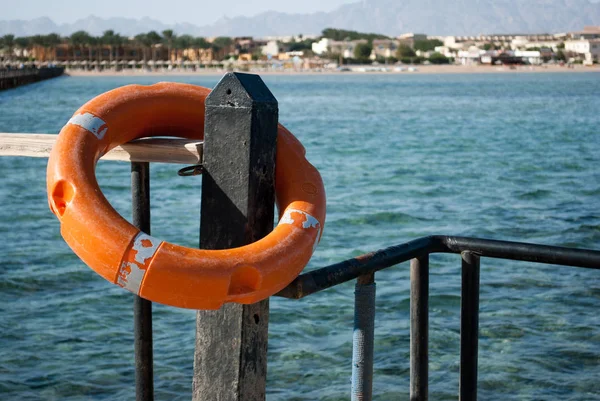 在柱子和屏障上的救生圈特写 救生圈为溺水的水安全 紧急救援设备 救生圈在黑柱子上 海滨背景 — 图库照片